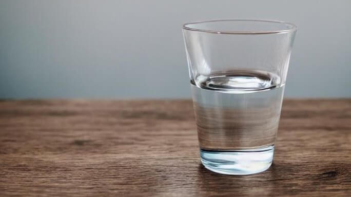 glass of water sits on wood table